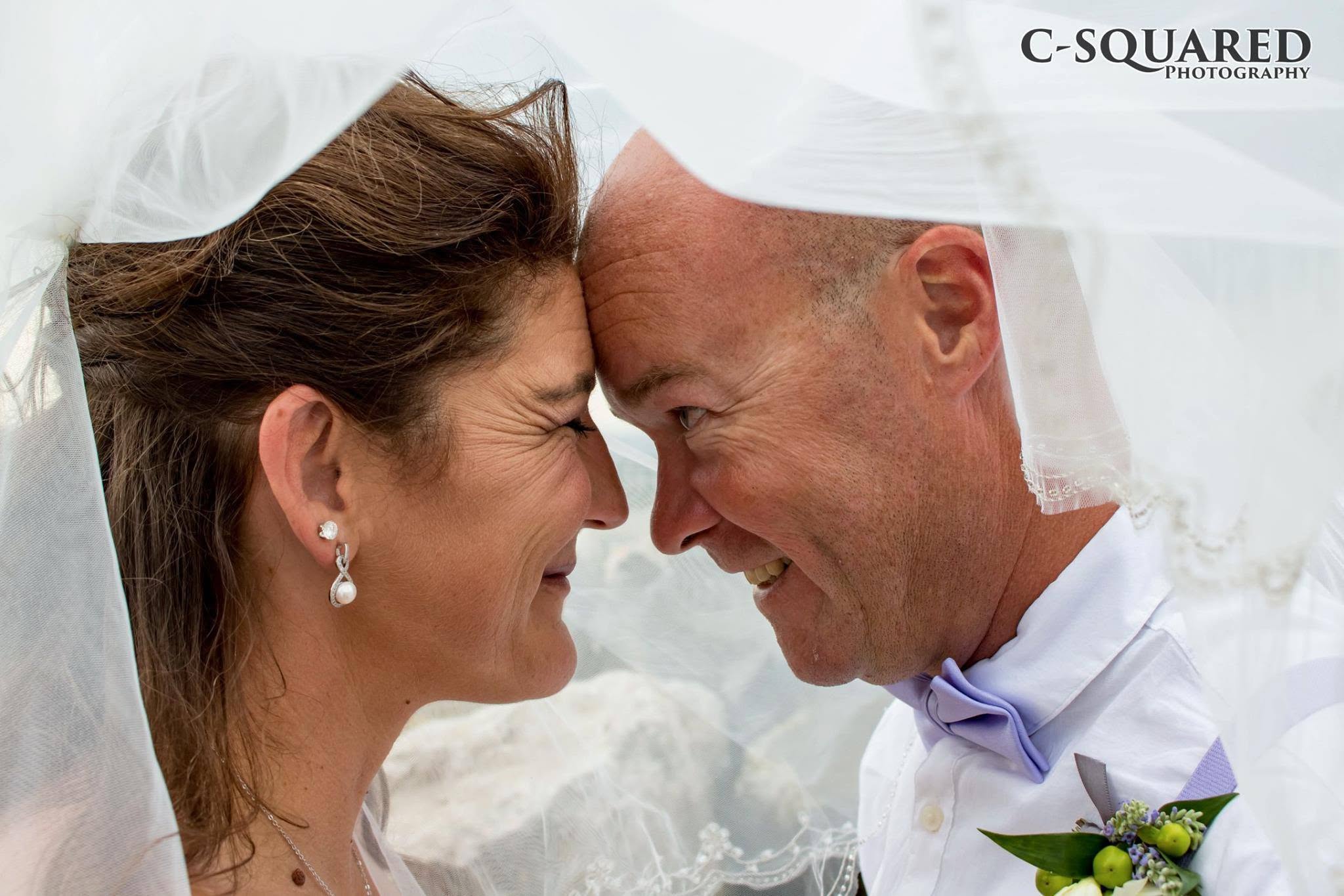 Newlyweds sharing a smile beneath a wedding veil