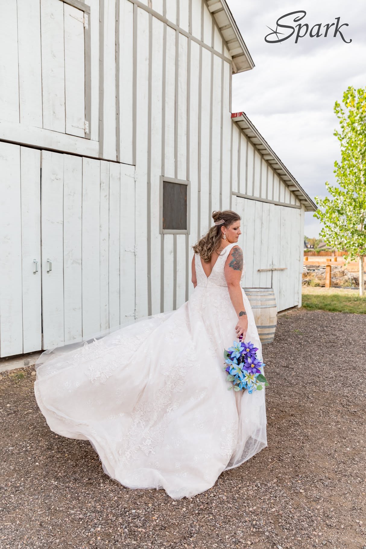 Bride with a flowing veil beside a white barn
