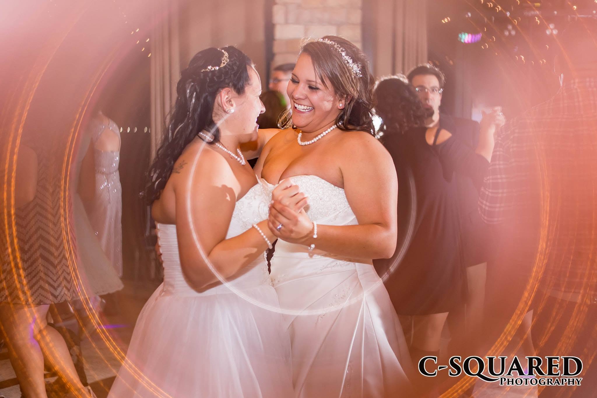 Two brides smiling together on the reception dance floor